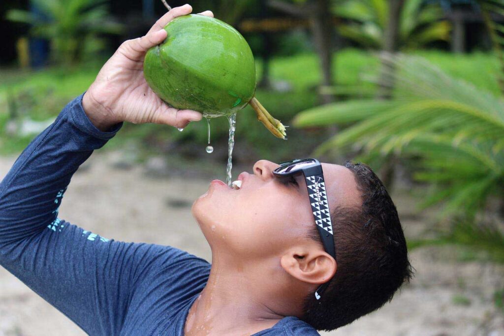 Surfista con Bomber gafas de sol y bebiendo un coco