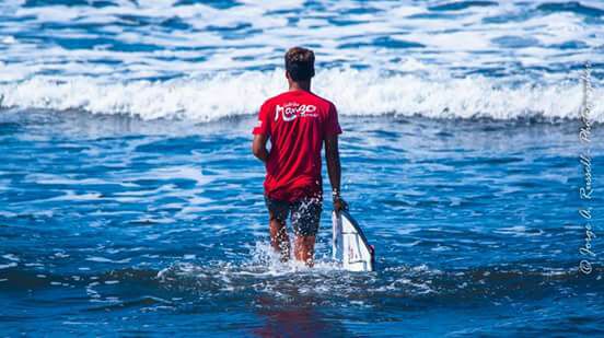 Bomber Floating Eyewear Latin America surfista caminando hacia las olas en Jacó