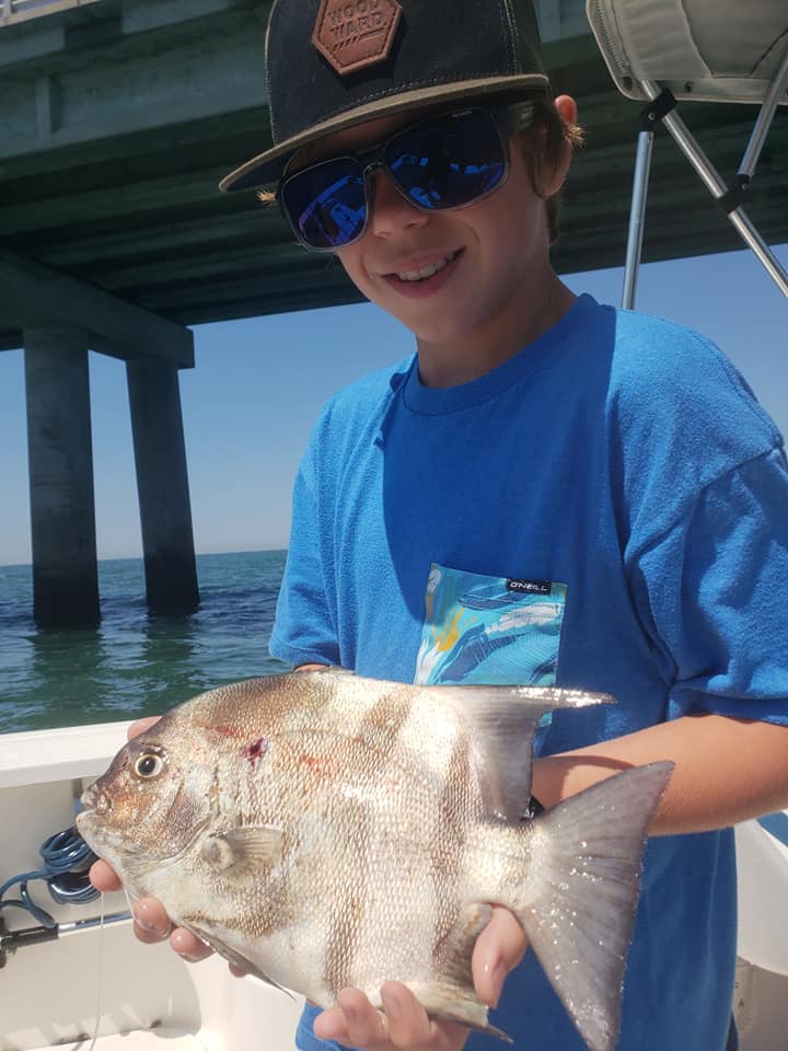 Joven pescador mostrando un gran pez espada mientras usa Bomber gafas de sol