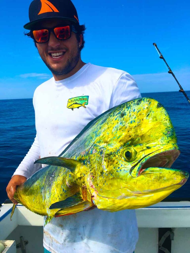 Feliz pescador sosteniendo un gran tambor amarillo en un barco mientras usa gafas de sol flotantes polarizadas Bomber