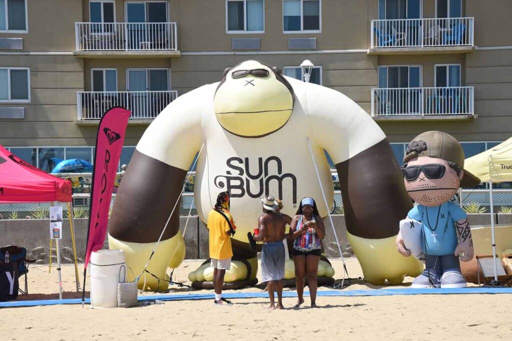 Mono gigante SUNBUM en la arena del Concurso de Surf de la Costa Este de Virginia Beach, donde Bomber Floating Eyewear es un patrocinador