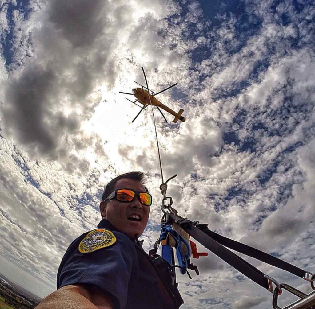 Trabajador de rescate escalando cuerda desde helicóptero con gafas de sol Bomber Safety